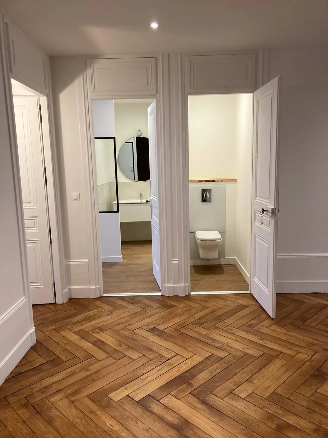 Parquet bâtons rompus restauré et enfilade de portes moulurées à impostes, appartement haussmannien rénové