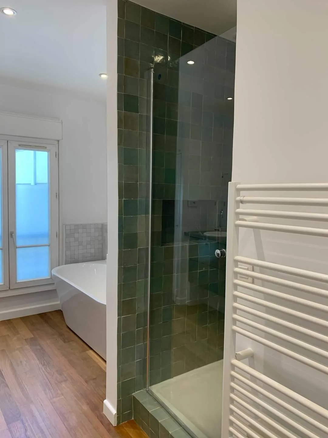 Salle de bains en zellige vert avec baignoire îlot, rénovation d'appartement haussmannien